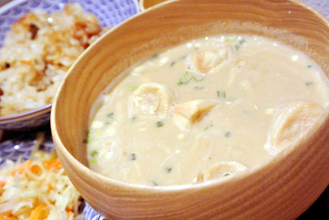 豆腐と白味噌・麦味噌をメインに作られた「はじまりの白」に、ネギとお麩のトッピング。写真は、炊き込み御飯（または玄米ご飯）、ガーリックが効いたペペロンチーノ風切り干し大根、蕗味噌がセットになった「一汁一菜セット」です。